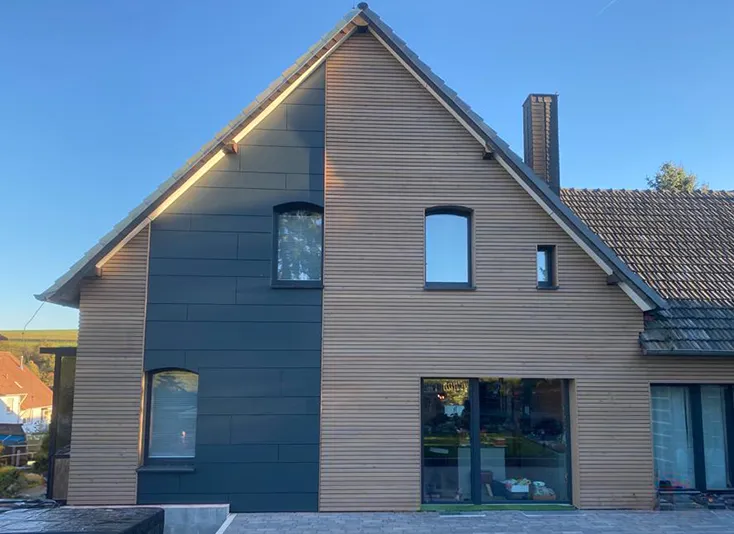 Wohnhaus mit Leistenfassade aus Lärche und dunklen Fassadenplatten in Korbach