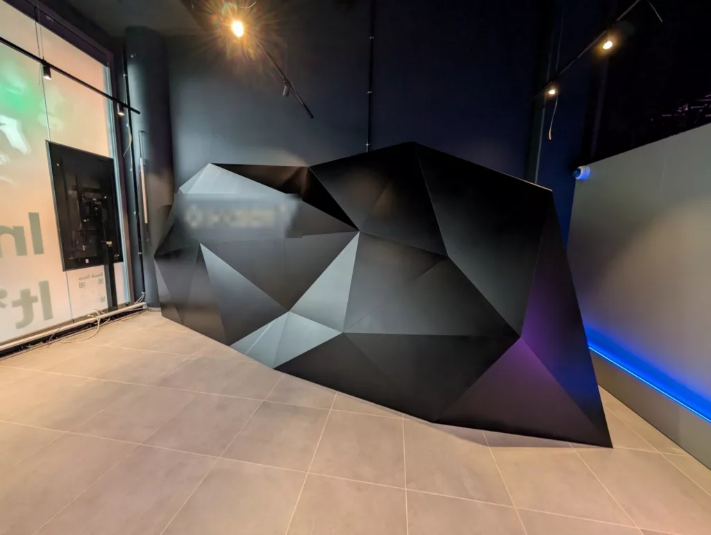 Facettierte Designwand in Schwarz mit hinterleuchtetem Logo in einem Store in Berlin